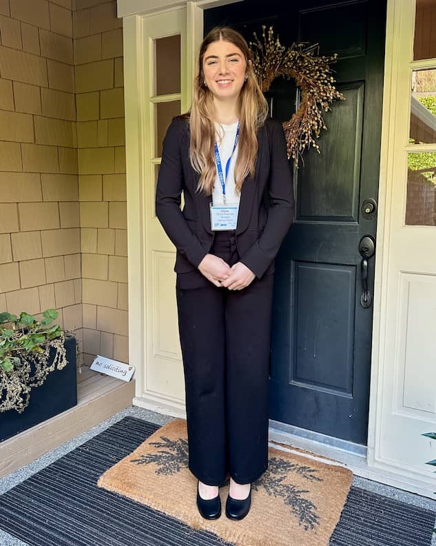 Young woman in black suit and Black PIAR Performance Heels standing on front porch