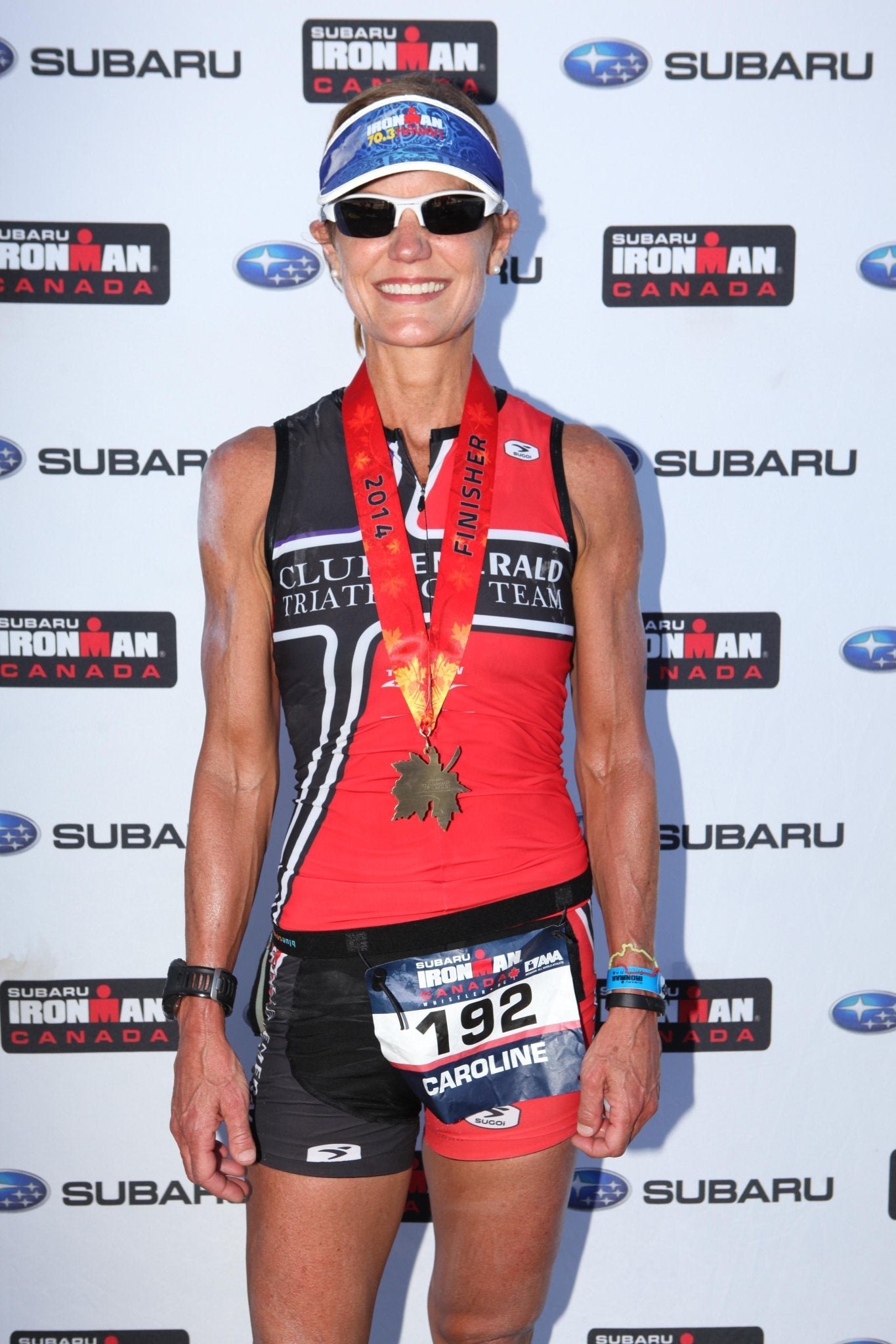 Caroline Hughes after completing an Ironman Triathlon in Canada, wearing race medal and tri gear