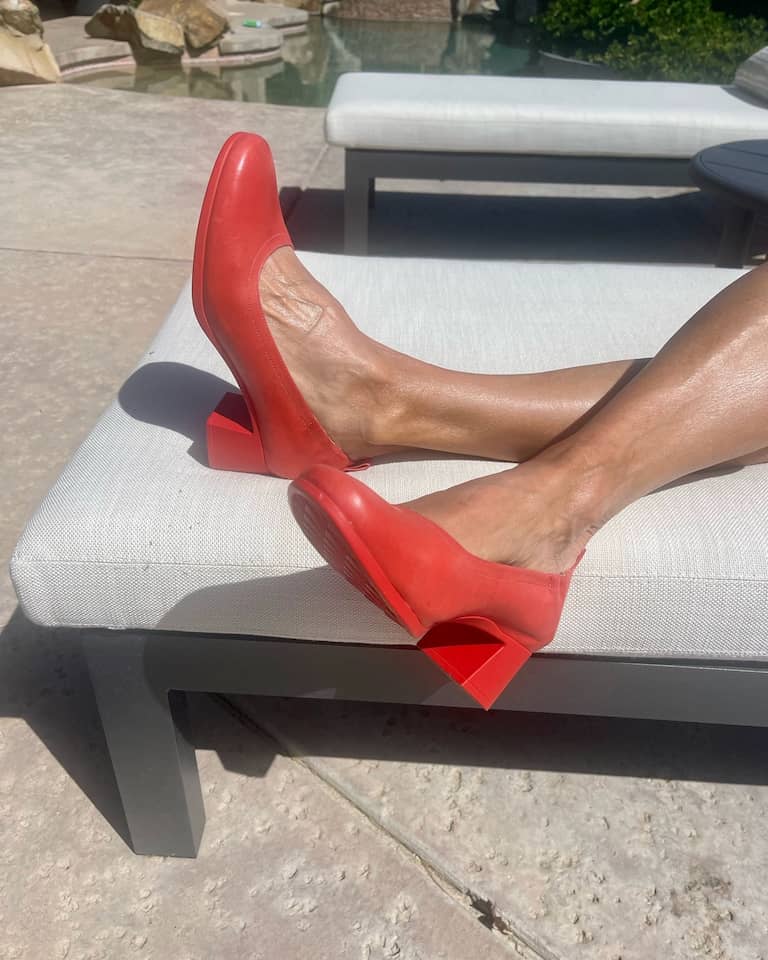 Woman wearing Lava Red PIAR Performance Heels on lounge chair