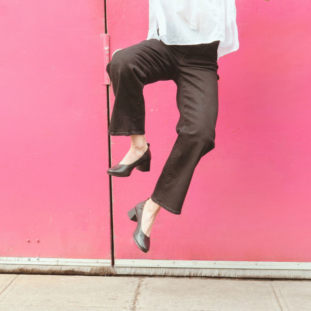 The Performance Heel by PIAR - Woman In Stylish and Comfortable Black Leather Block Heels Kicking Feet In the Air
