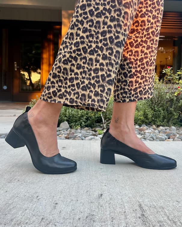 Woman in leopard pants wearing Black PIAR Performance Heels on patio