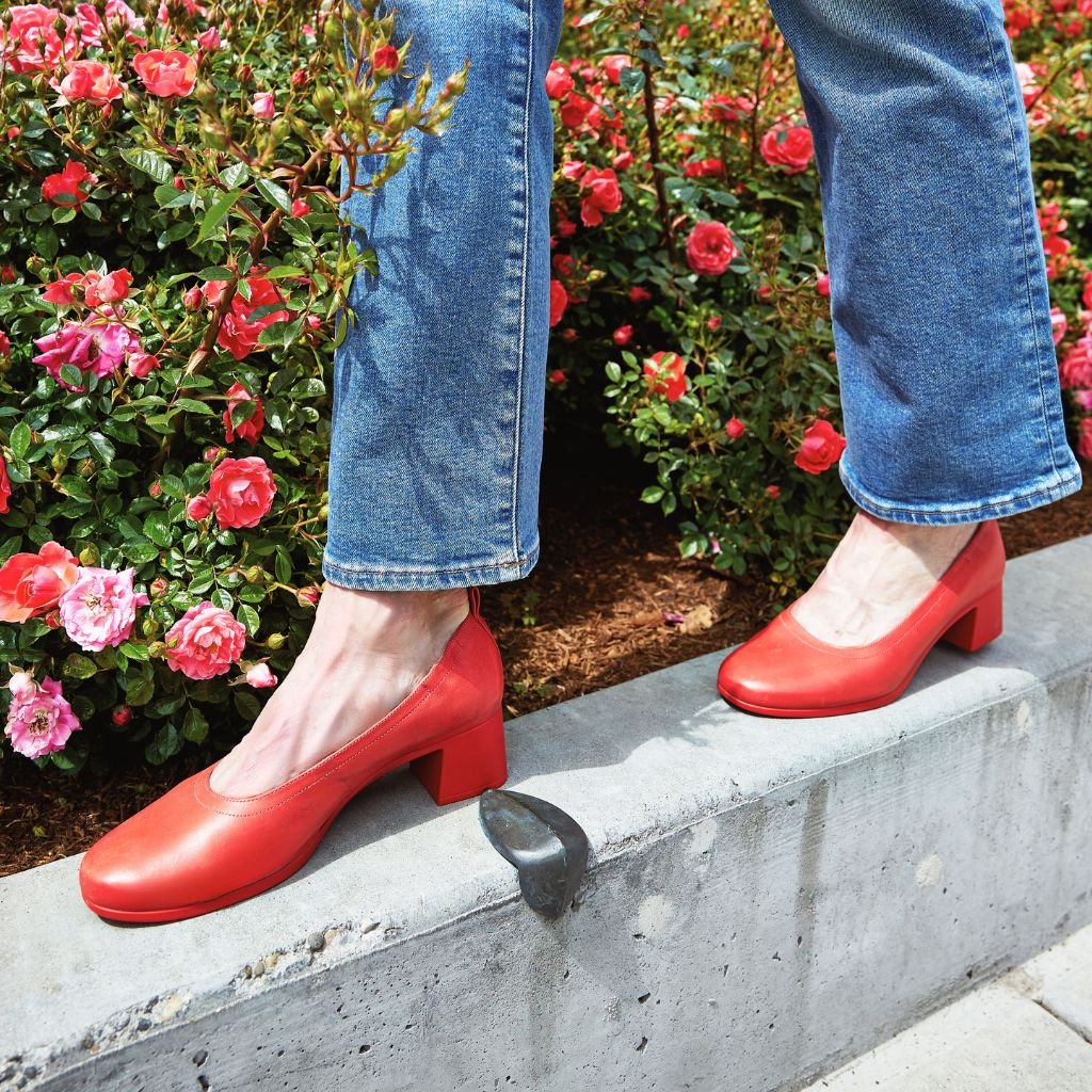 The Performance Heel by PIAR - Woman Wearing Stylish and Comfortable Red Leather Block Heel Pumps In Front of Roses