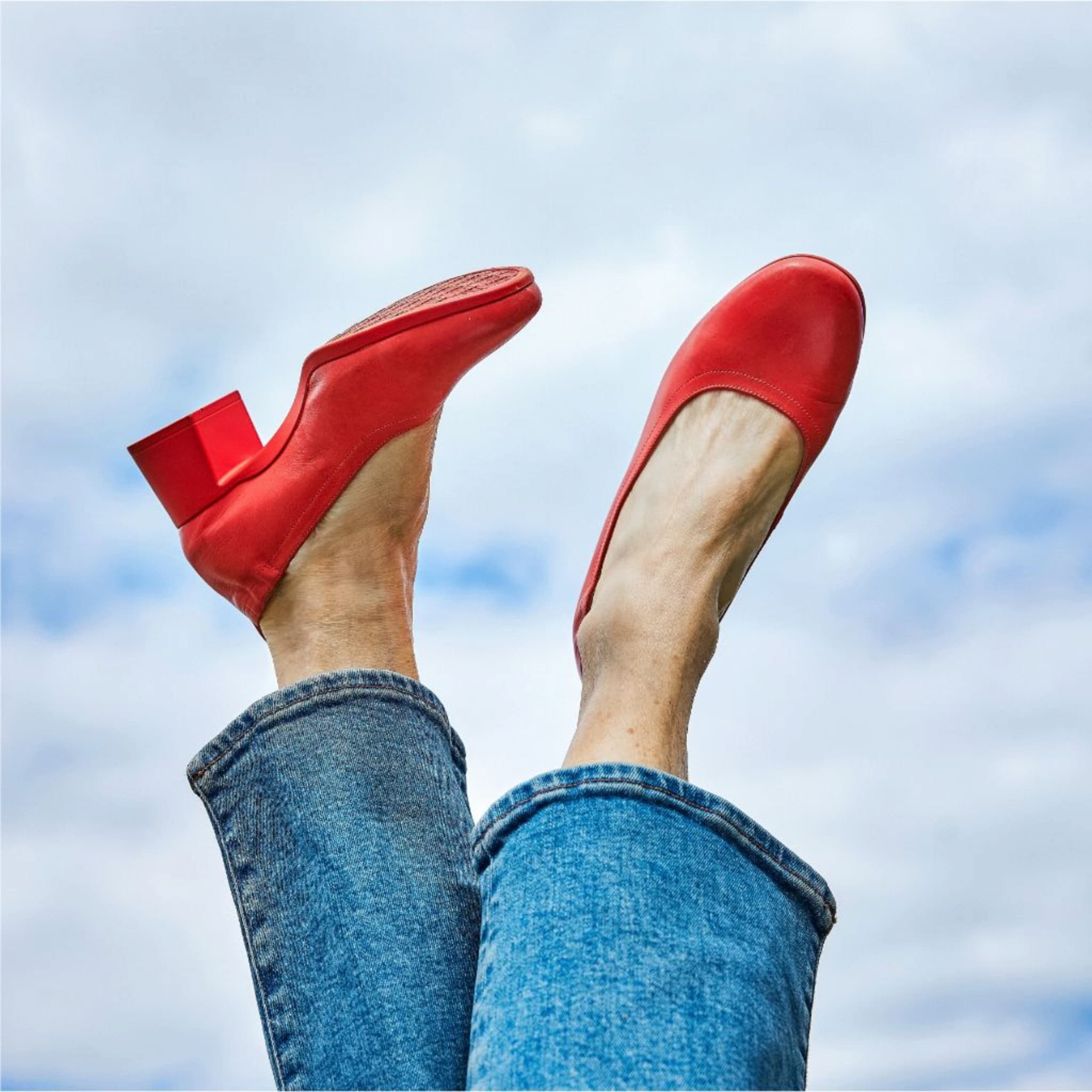 Legs in jeans raised against sky wearing Lava Red PIAR Performance Heels