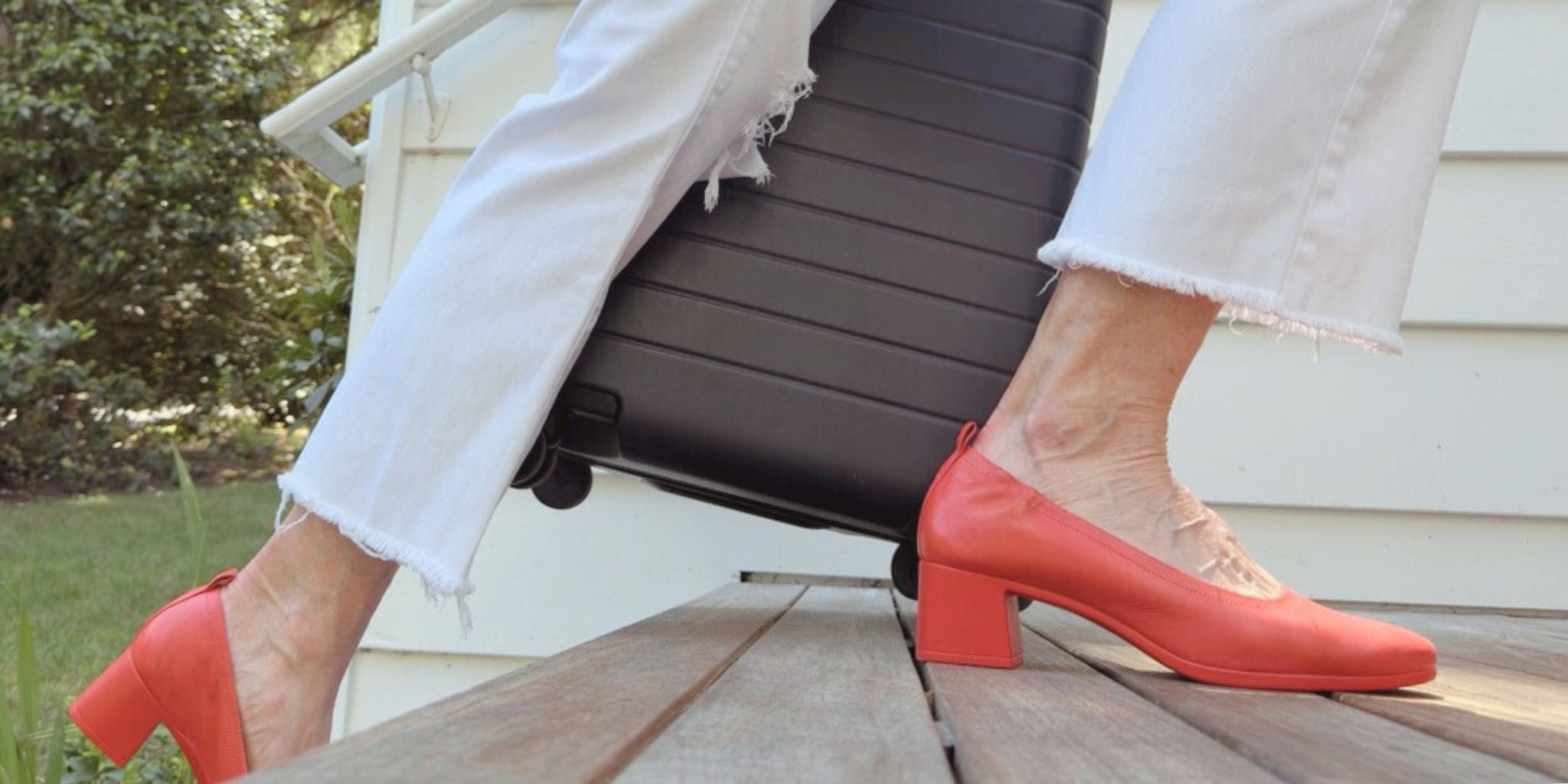 Woman walking up porch steps with luggage in Lava Red PIAR Performance Heels
