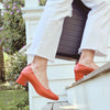 The Performance Heel by PIAR - Woman In Stylish and Comfortable Red Leather Block Heels Bounding Up Stairs with Luggage